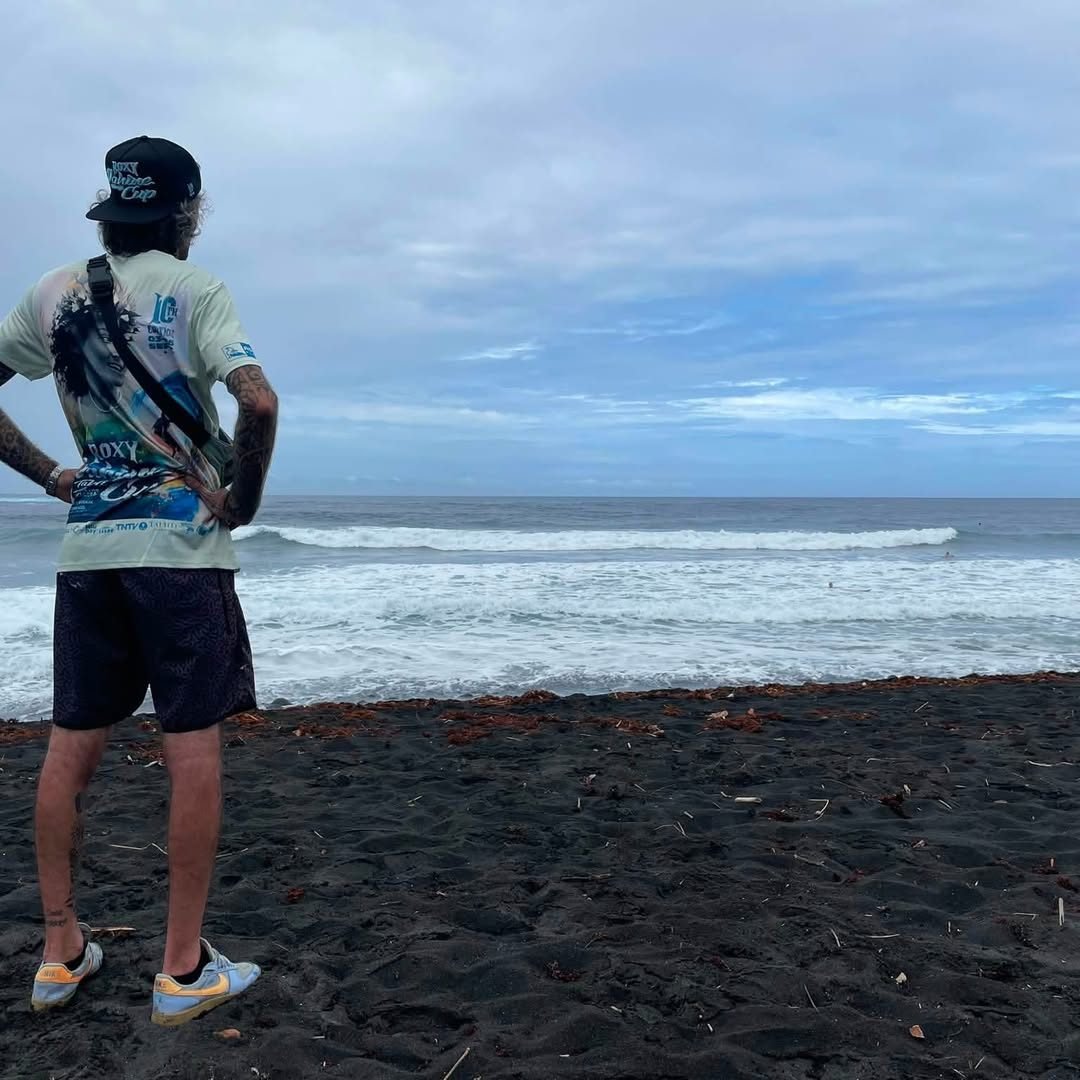 Spectateur face aux vagues sur la plage de sable noir